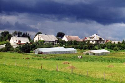A rather typical scene looking into a small village in Lithuania.  The fields are small and the houses modest, but new techniques such as temporary hot-houses are used to extend the otherwise short growing season. 